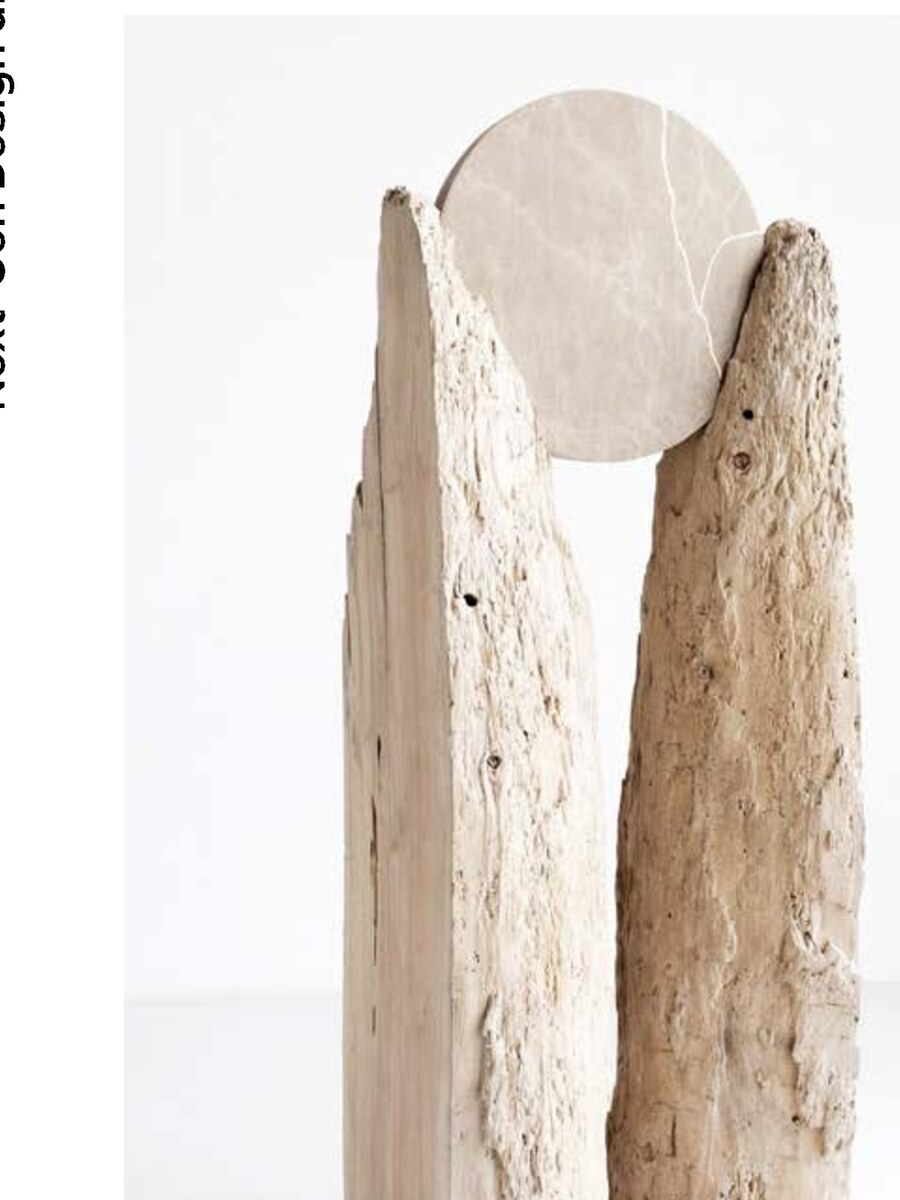 Two eroded travertine slabs cradling a pale disc — the origin form of the host object.
